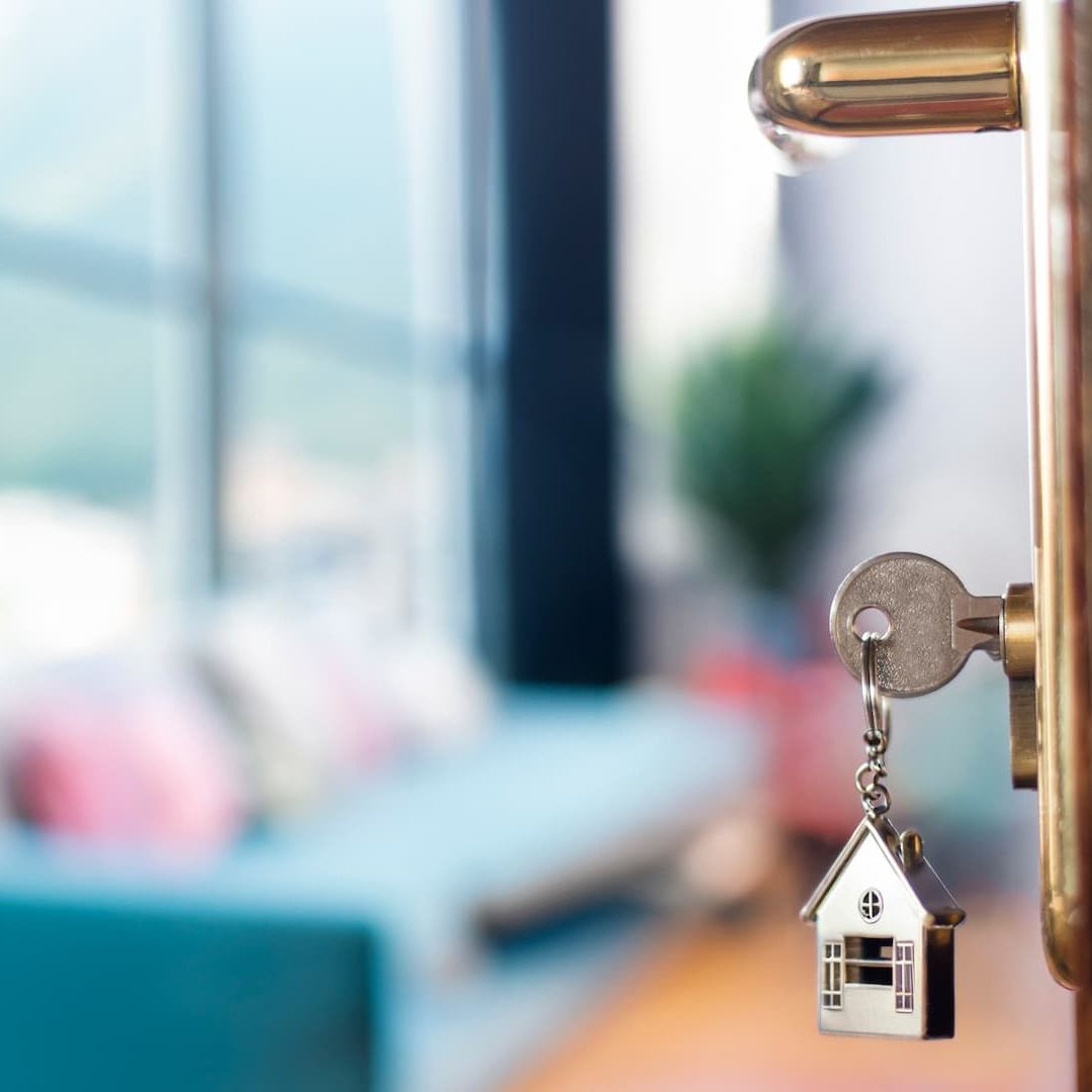 Schlüssel mit Haus-Anhänger steckt in einer Wohnungstür
